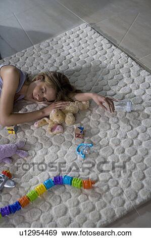 Stock Photo - Young mother sleeping on carpet. Fotosearch