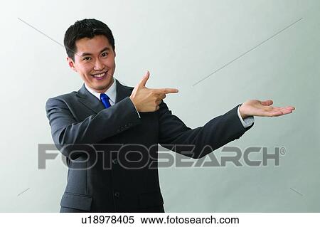 Stock Photography - Toothy Smile, Standing, Gesturing, Waist-Up, Pointing. Fotosearch