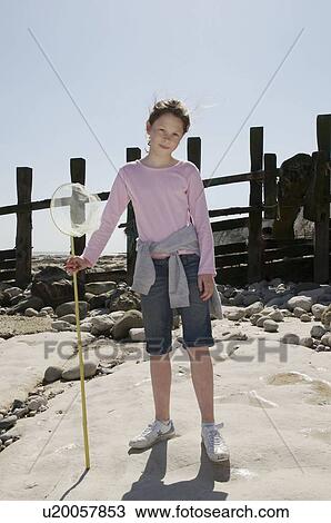 Stock Image - Girl with fishing net on beach. Fotosearch