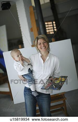 Mother holding baby in front of easel View Large Photo Image Picture - Mother holding baby in front of easel. Fotosearch