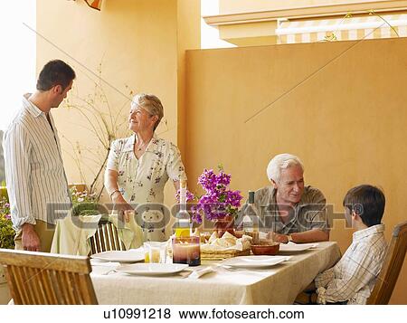 Multi-generational family talking at dining table on balcony View Large Photo Image Stock Photo - Multi-generational family talking at dining table on balcony. Fotosearch