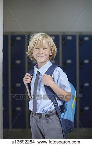 Picture - School boy holding backpack. Fotosearch