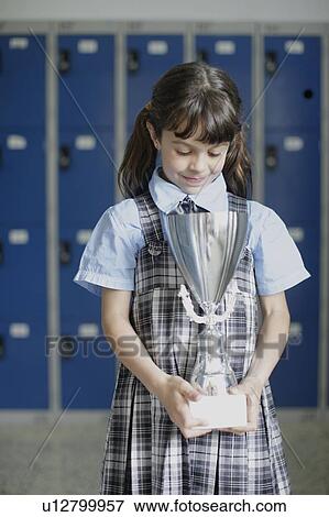Stock Photo - School girl looking down at trophy. Fotosearch