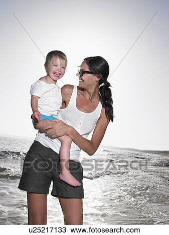 Woman holding a young girl at the beach smiling. View Large Photo Image Stock Image - Woman holding a young girl at the beach smiling.. Fotosearch