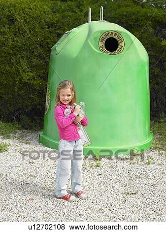 Young girl (5-7) standing in front of recycling bin holding glass bottles, Alicante, Spain, View Large Photo Image Stock Photo - Young girl (5-7) standing in front of recycling bin holding glass bottles, Alicante, Spain,. Fotosearch