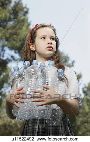 Stock Image - Young girl holding empty bottles. Fotosearch