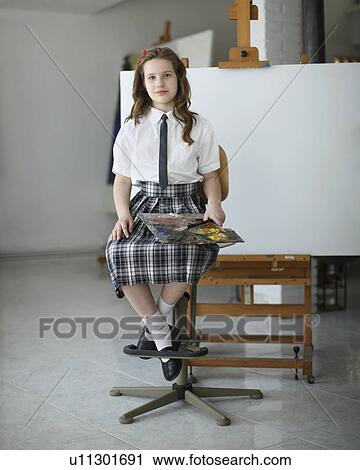 Stock Image - Young girl sitting with paints. Fotosearch