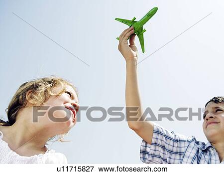 Boy and girl looking up at toy plane View Large Photo Image Stock Photo - Boy and girl looking up at toy plane. Fotosearch