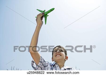 Stock Image - Boy holding toy plane aloft. Fotosearch