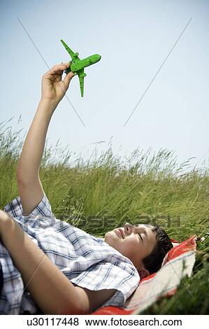 Boy lying down playing with plane View Large Photo Image Stock Photo - Boy lying down playing with plane. Fotosearch