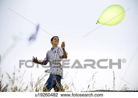 Stock Image - Boy running with balloon. Fotosearch
