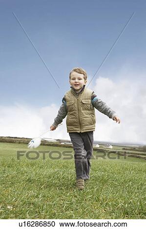 Stock Image - Boy running with windmill. Fotosearch
