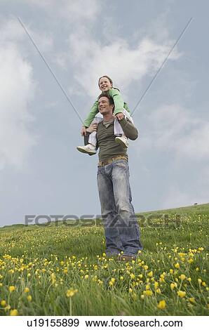 Daughter sits on father's shoulders View Large Photo Image Stock Photo - Daughter sits on father's shoulders. Fotosearch