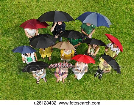 Group of people on grass holding umbrellas View Large Photo Image Stock Image - Group of people on grass holding umbrellas. Fotosearch