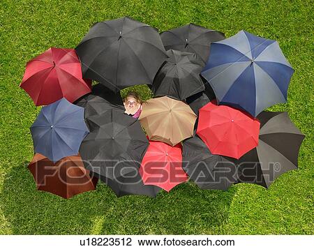 Stock Image - Group of umbrellas from above with one face looking up. Fotosearch