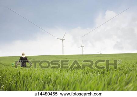 Stock Photography - Pregnant woman walking through wind farm. Fotosearch