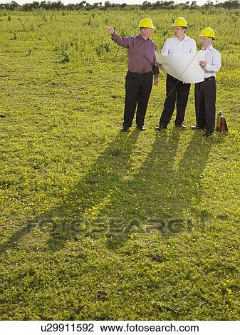 Stock Image - Three surveyors on a field.. Fotosearch