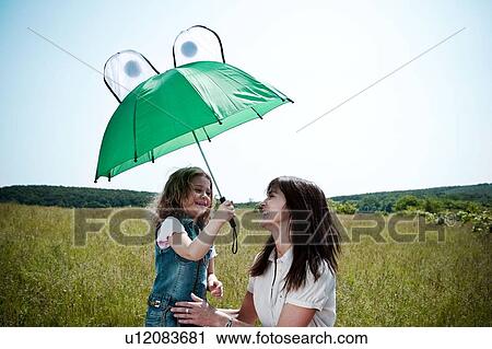 Woman and girl playing with umbrella View Large Photo Image Stock Image - Woman and girl playing with umbrella. Fotosearch