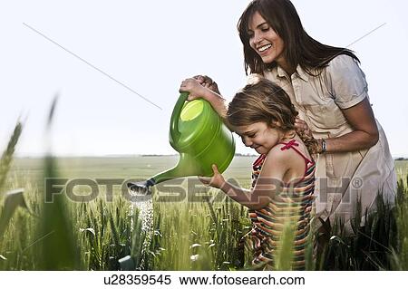 Woman helping child with watering can View Large Photo Image Stock Photography - Woman helping child with watering can. Fotosearch
