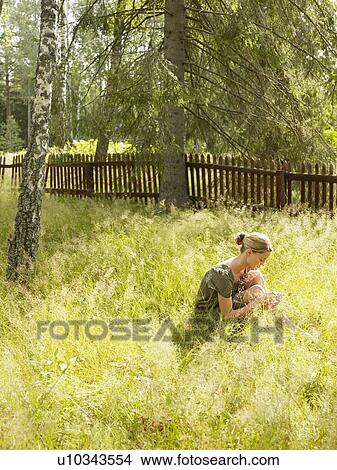 Picture - Woman in the grass reading a book.. Fotosearch