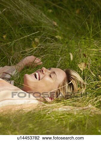 Woman lying in the grass with eyes closed laughing. View Large Photo Image Stock Image - Woman lying in the grass with eyes closed laughing.. Fotosearch