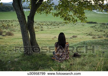 Stock Photo - Woman sitting under tree.. Fotosearch