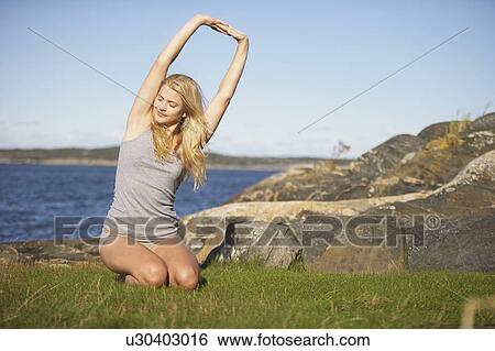 Young Woman doing Yoga on grass by sea. View Large Photo Image Stock Photograph - Young Woman doing Yoga on grass by sea.. Fotosearch