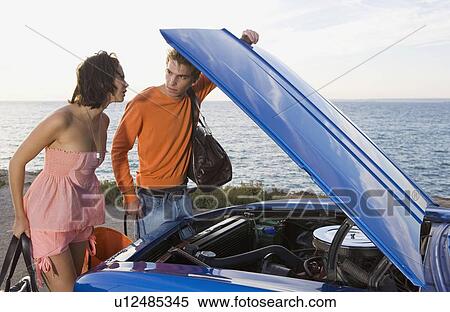 Stock Photography - Man and woman looking under car bonnet.. Fotosearch