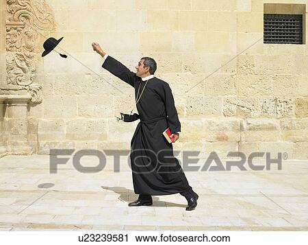 Priest reaching for his hat blowing in the wind, Alicante, Spain, View Large Photo Image Stock Image - Priest reaching for his hat blowing in the wind, Alicante, Spain,. Fotosearch