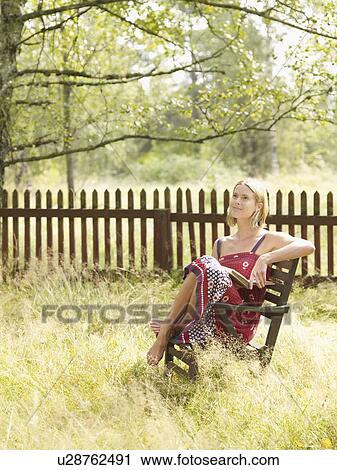 Woman sitting in chair by wooden fence with book. View Large Photo Image Stock Image - Woman sitting in chair by wooden fence with book.. Fotosearch