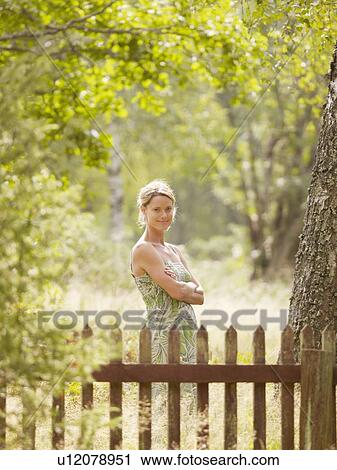 Woman standing by wooden fence smiling. View Large Photo Image Stock Image - Woman standing by wooden fence smiling.. Fotosearch