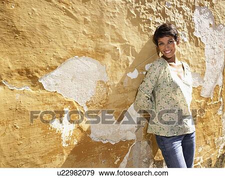 Stock Photo - Woman standing up against a wall.. Fotosearch