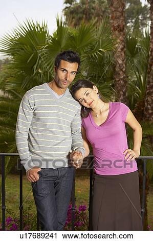 Young couple holding hands standing on balcony, smiling, portrait View Large Photo Image Stock Image - Young couple holding hands standing on balcony, smiling, portrait. Fotosearch