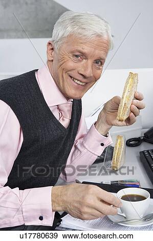 Stock Photo - Businessman having light bite. Fotosearch