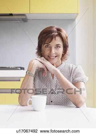 Stock Image - Portrait of senior woman in kitchen. Fotosearch