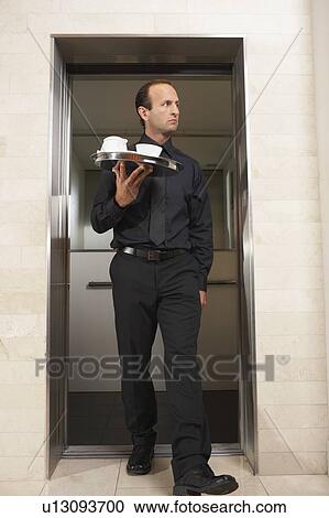 Waiter strolling out of an elevator View Large Photo Image Stock Image - Waiter strolling out of an elevator. Fotosearch