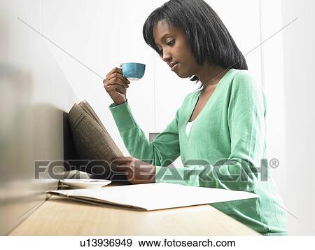 Stock Photo - Woman having a coffee, reading newspaper. Fotosearch