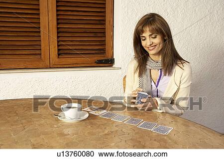 Woman having Coffeee while playing cards, smiling View Large Photo Image Stock Image - Woman having Coffeee while playing cards, smiling. Fotosearch