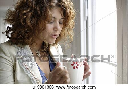 Stock Image - Woman holding cup of warm drink. Fotosearch