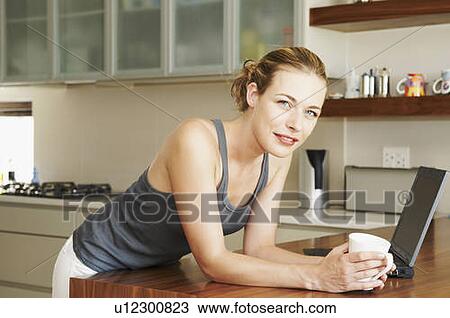 Stock Image - Woman in kitchen looking at camera. Fotosearch