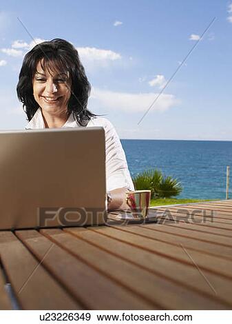 Woman on laptop out doors on decking View Large Photo Image Stock Photo - Woman on laptop out doors on decking. Fotosearch