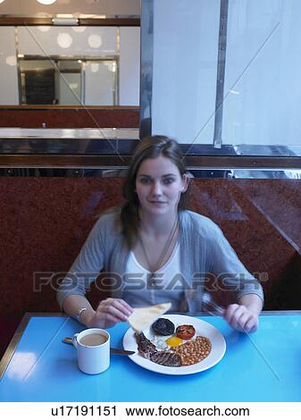 Young woman eating fried breakfast in cafe, portrait View Large Photo Image Stock Image - Young woman eating fried breakfast in cafe, portrait. Fotosearch