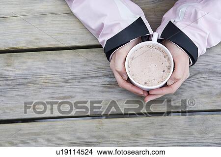 Young woman's hands holding cup of hot chocolate, close-up, high angle view View Large Photo Image Picture - Young woman's hands holding cup of hot chocolate, close-up, high angle view. Fotosearch
