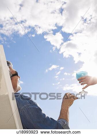 Senior man relaxing in deckchair accepting drink View Large Photo Image Stock Image - Senior man relaxing in deckchair accepting drink. Fotosearch