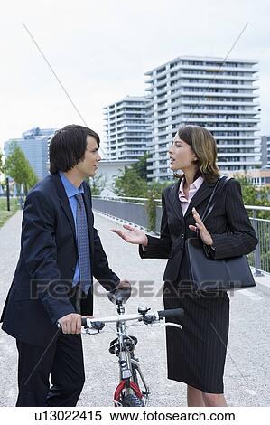 Businessman and woman discussing in-between bike. View Large Photo Image Stock Photography - Businessman and woman discussing in-between bike.. Fotosearch