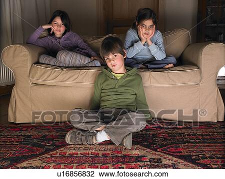 Stock Image - Children on sofa, watching tv. Fotosearch