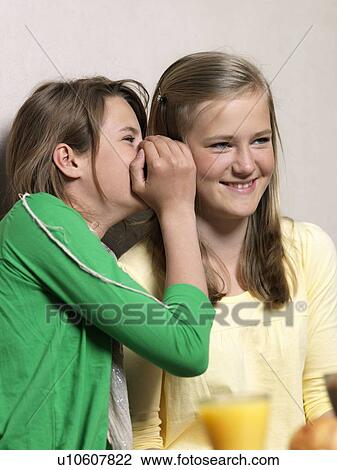 Girl whispering in friends ear View Large Photo Image Stock Image - Girl whispering in friends ear. Fotosearch