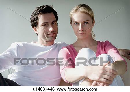 Stock Photograph - Portrait of a couple sitting on a sofa.. Fotosearch