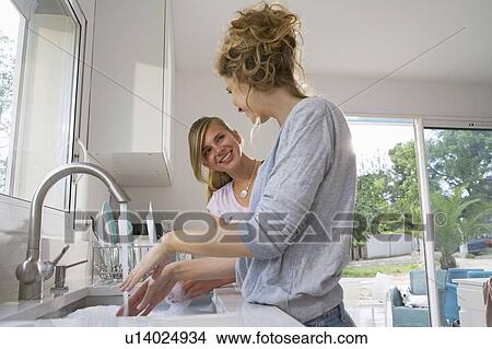 Sisters washing dishes, talking View Large Photo Image Picture - Sisters washing dishes, talking. Fotosearch