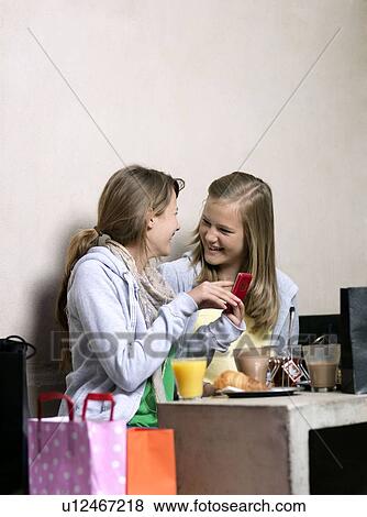 Two girls using cell phone View Large Photo Image Stock Photo - Two girls using cell phone. Fotosearch